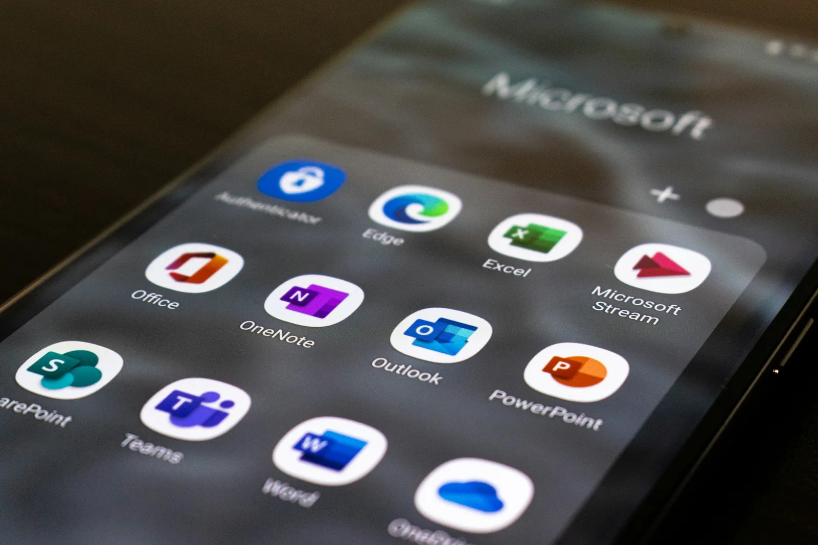 Phone screen showing Microsoft 365 app icons including Outlook, Teams, Word and Excel