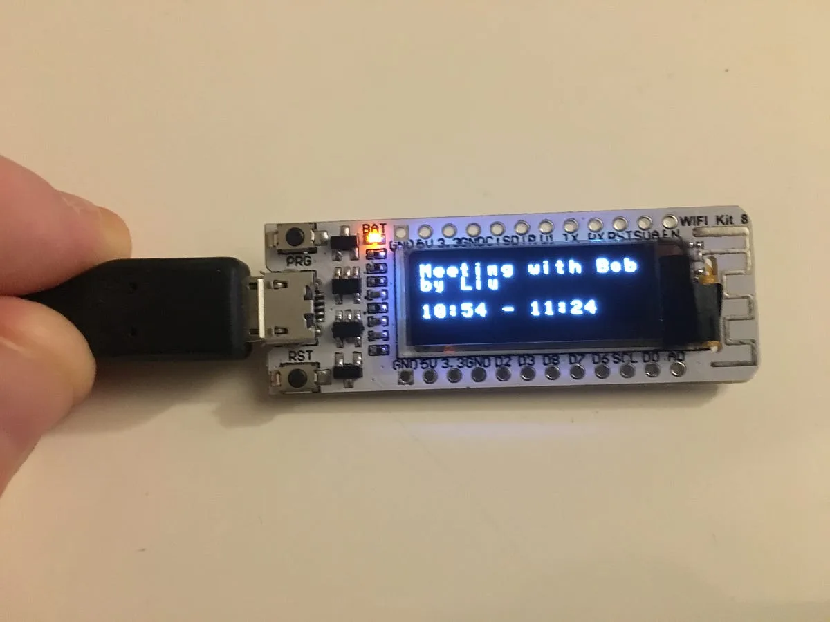 ESP8266 OLED display showing a booked meeting with its organiser and time range