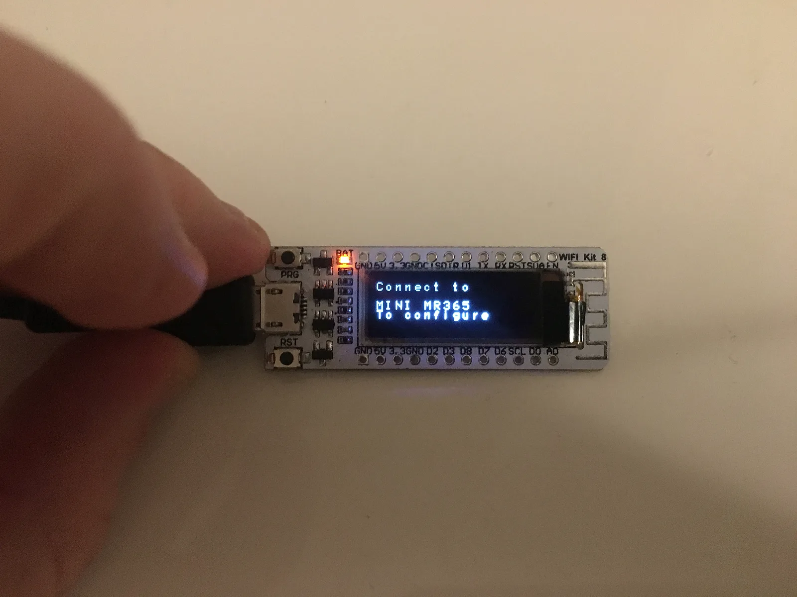 ESP8266 board held in hand showing Connect to MINI MR365 to configure on its OLED screen
