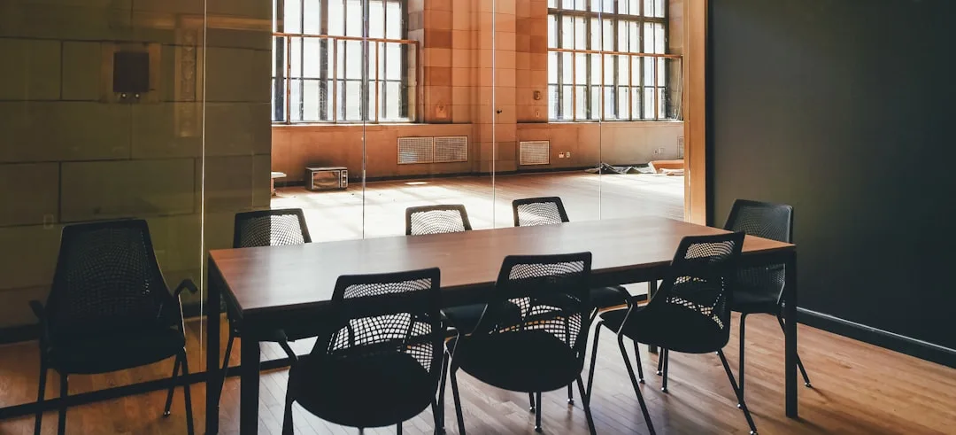 Empty meeting room with a long table, black chairs and a glass partition wall