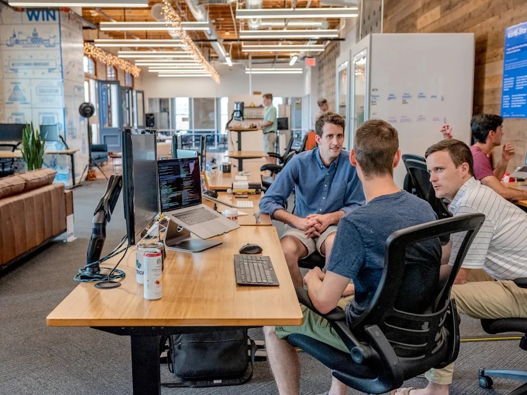 Colleagues talking at desks in an open plan office