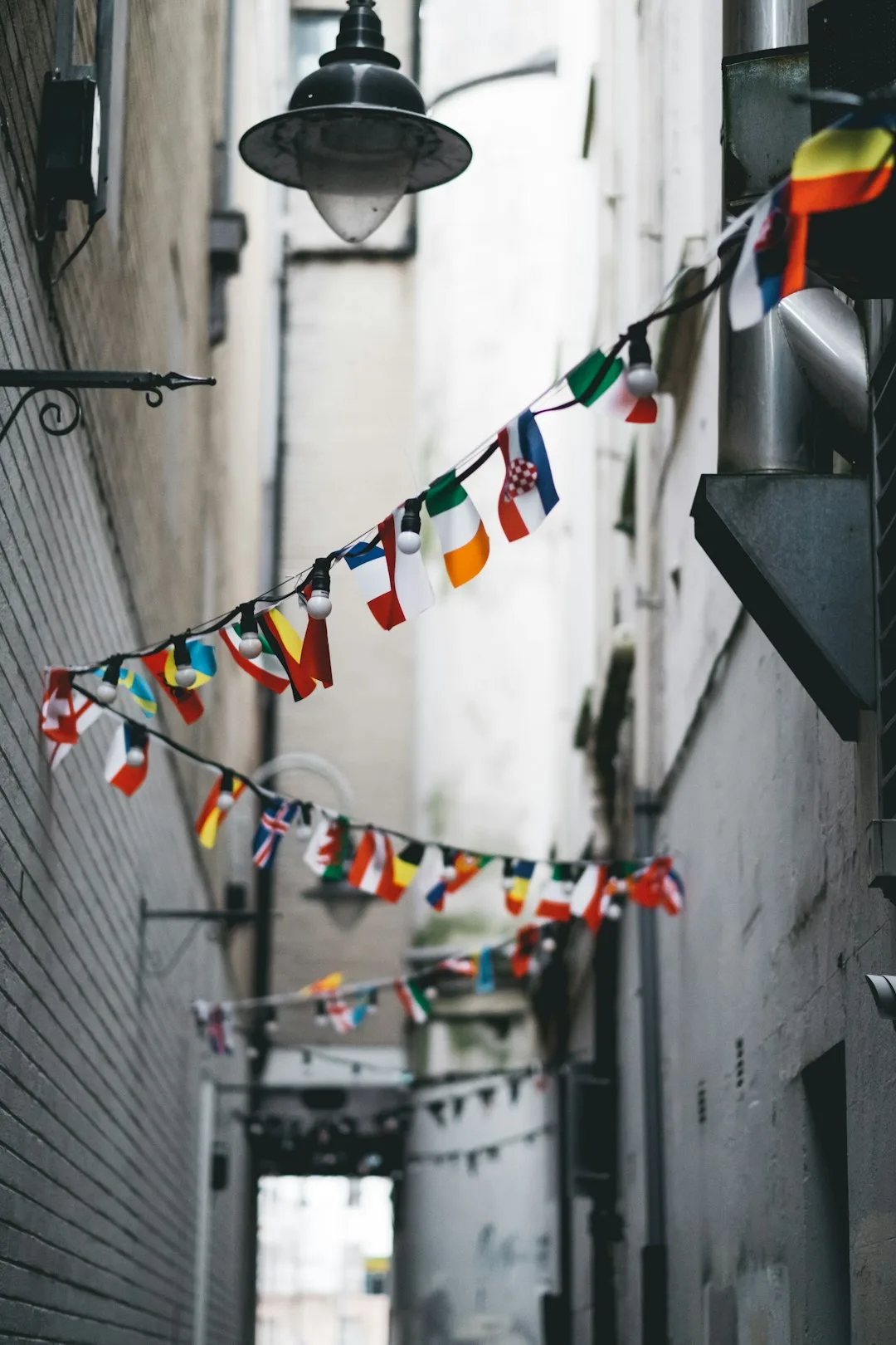 Strings of international flag bunting hanging across a narrow alley