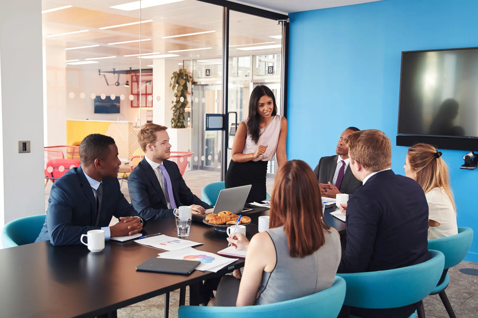 Colleagues meeting around a table in a brightly coloured modern office