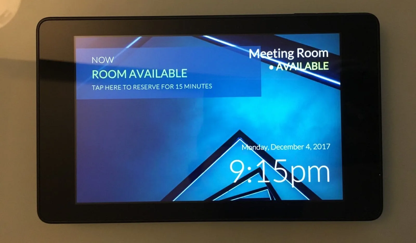 Amazon Fire tablet mounted on a wall showing the meeting room as available