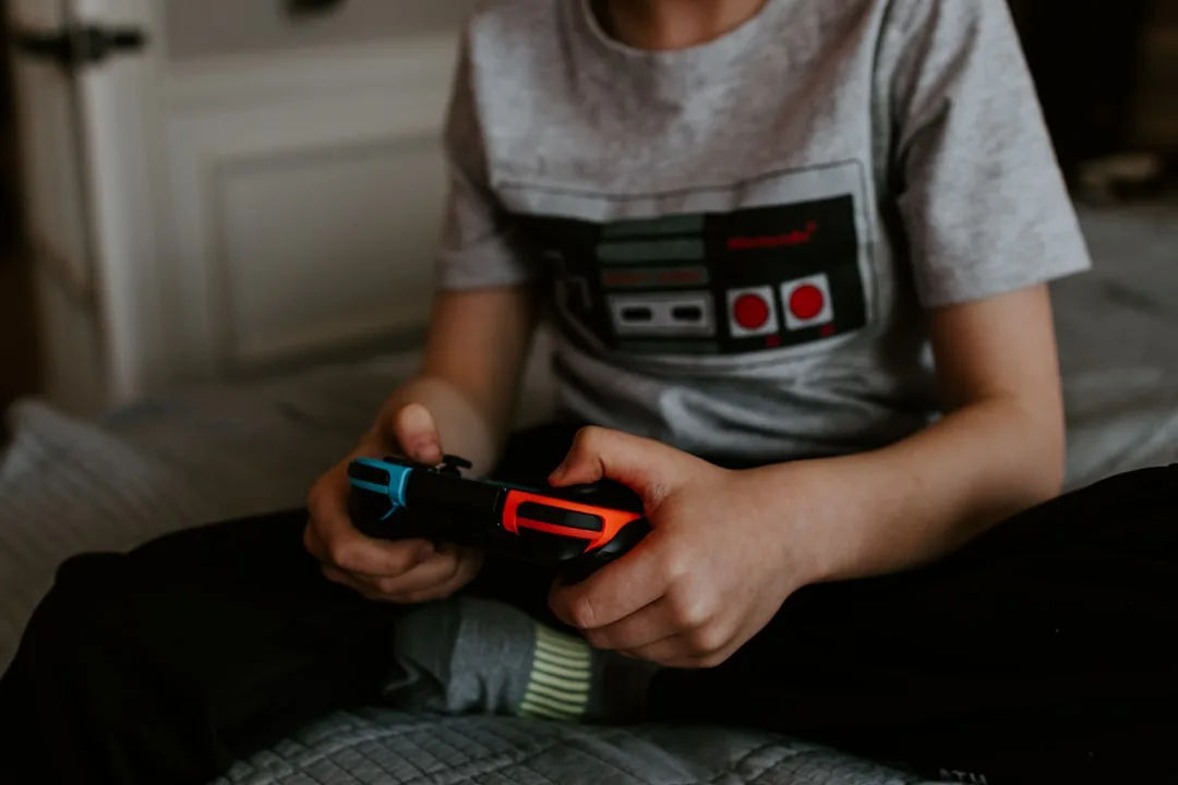 Child holding a Nintendo Switch controller while wearing a Nintendo t-shirt