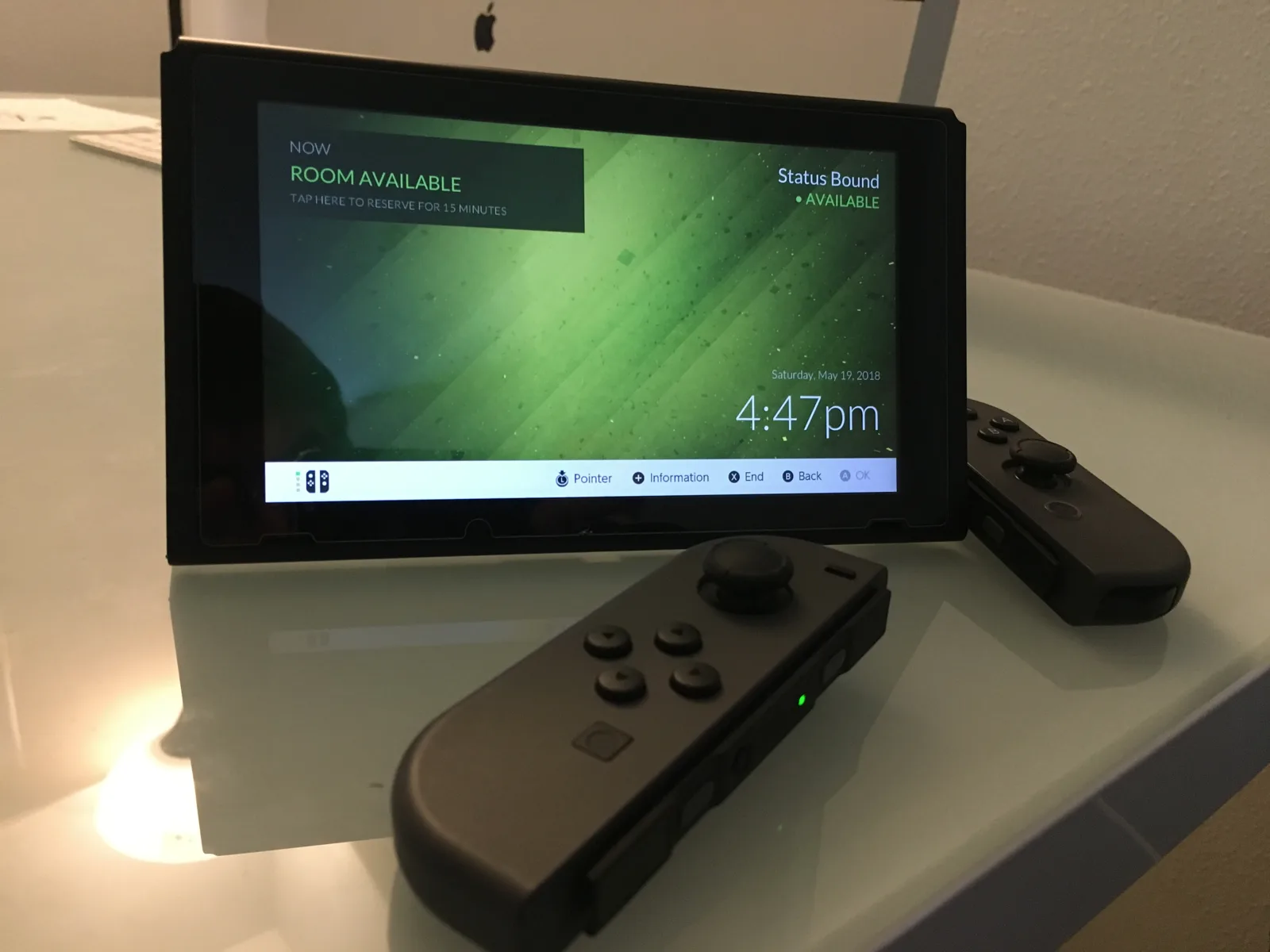 Nintendo Switch displaying a green meeting room status screen with its Joy-Con controllers detached