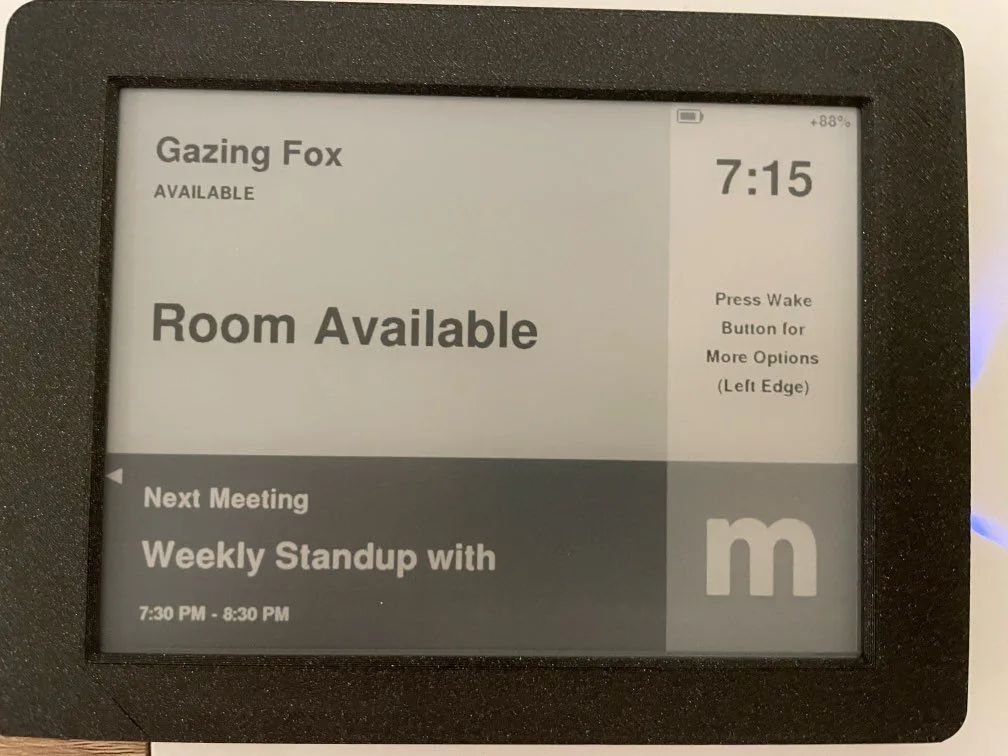 E-ink meeting room display showing the room available with the next meeting listed underneath