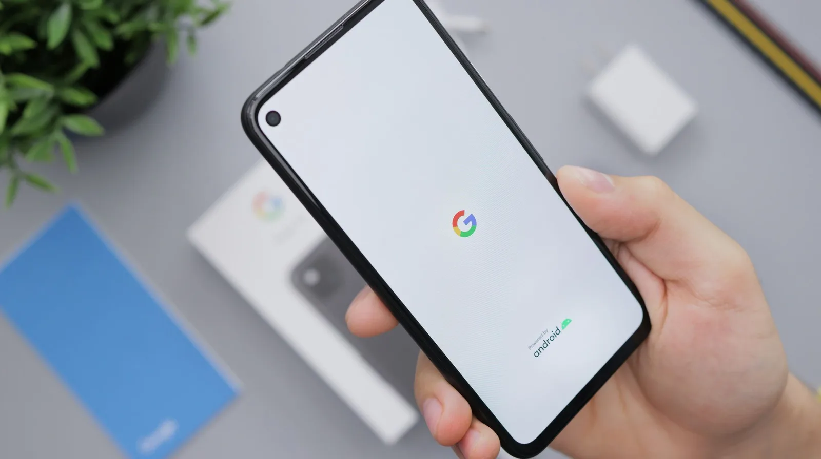 Hand holding an Android phone showing the Google logo on screen