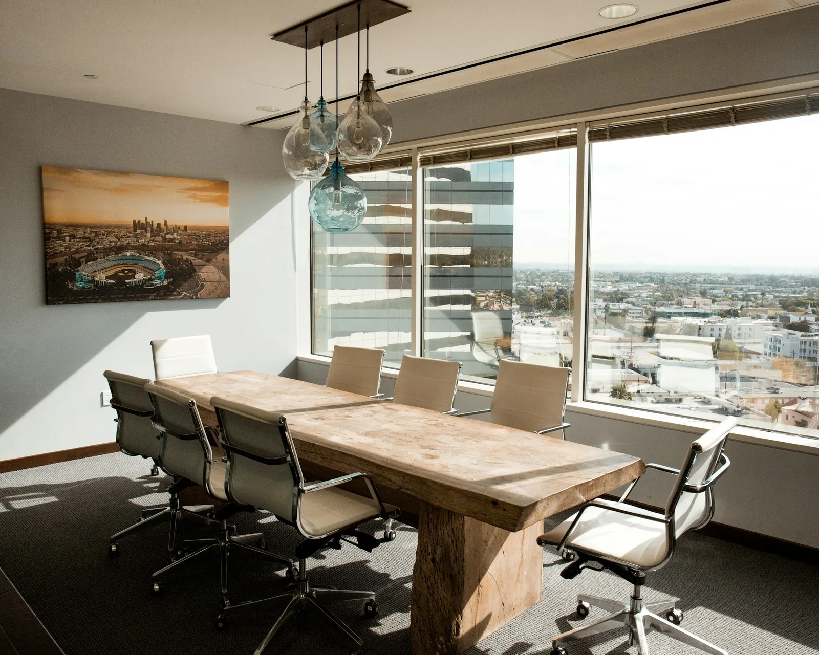 Boardroom with a live edge wooden table, leather chairs and a city view through the window