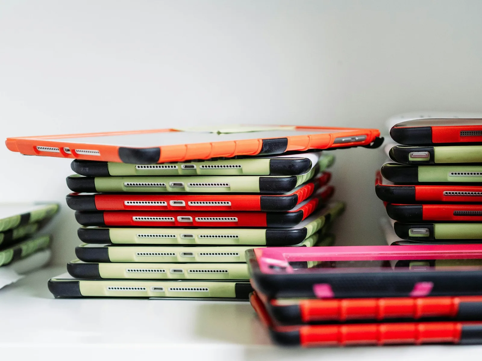 Stacks of tablets in orange and green protective cases