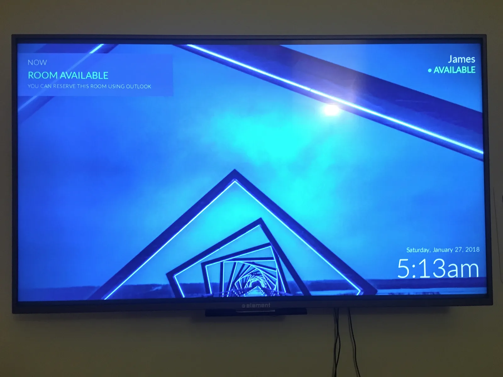 Wall mounted television showing the meeting room display with the room available