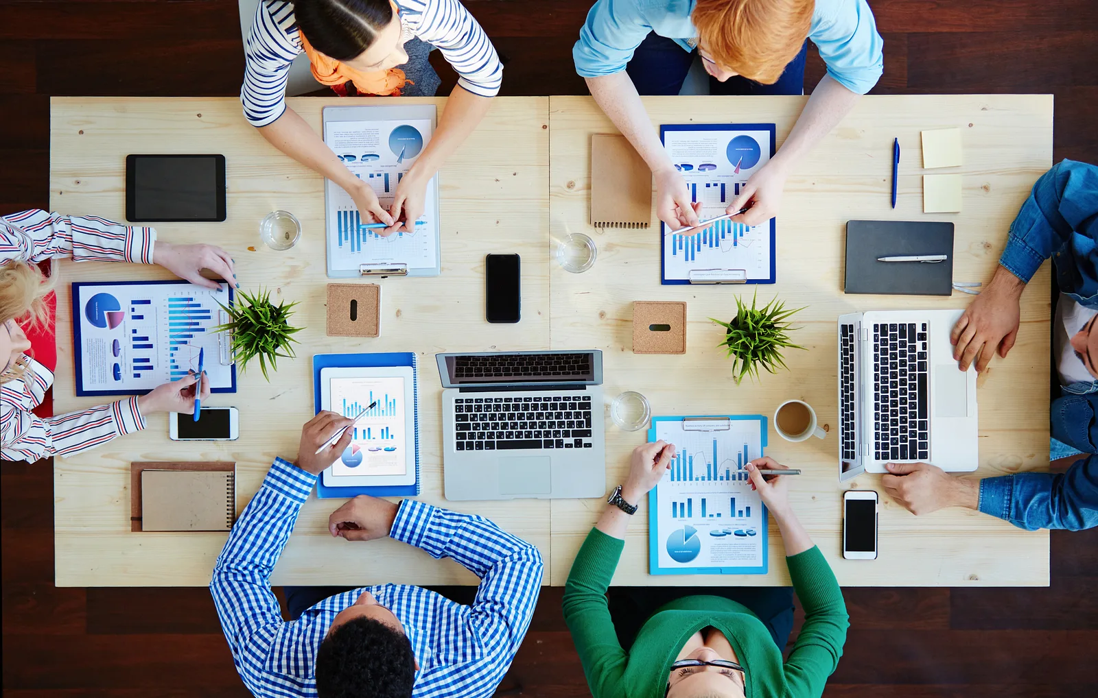 Overhead view of a team reviewing printed charts and tablets around a table